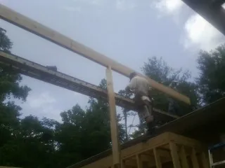 Carpenter setting a ridge beam over a new addition frame — Ice Dam Removal by Roofing Brothers in Holly