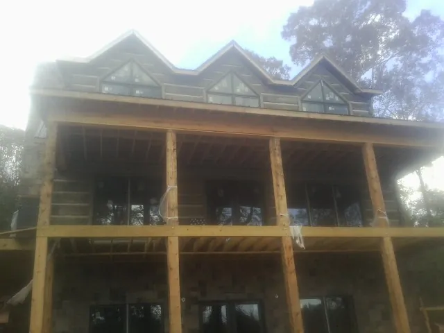 Dormers and porch framing on a large log home under construction — Roof Coating work by our crew in Holly