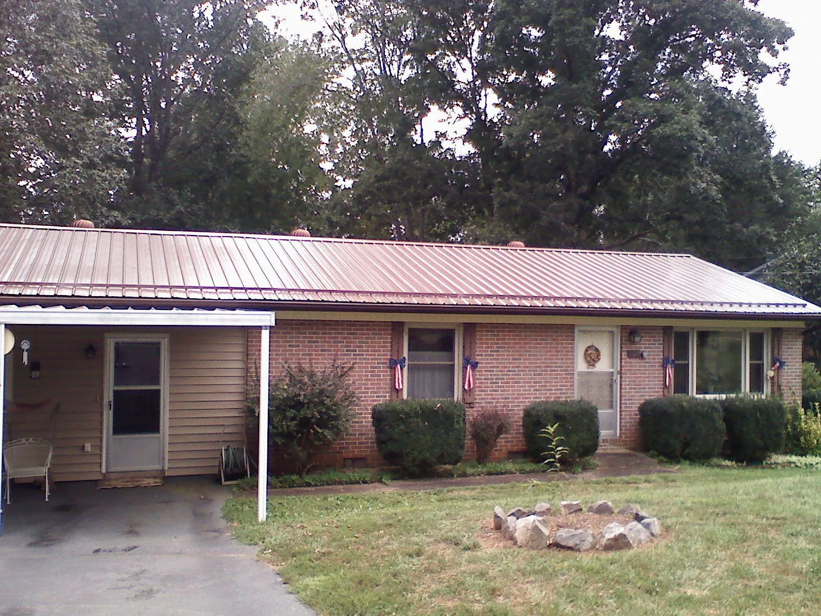 Bronze metal roof and carport on a brick ranch home — Roof Repair work by our crew in Holly